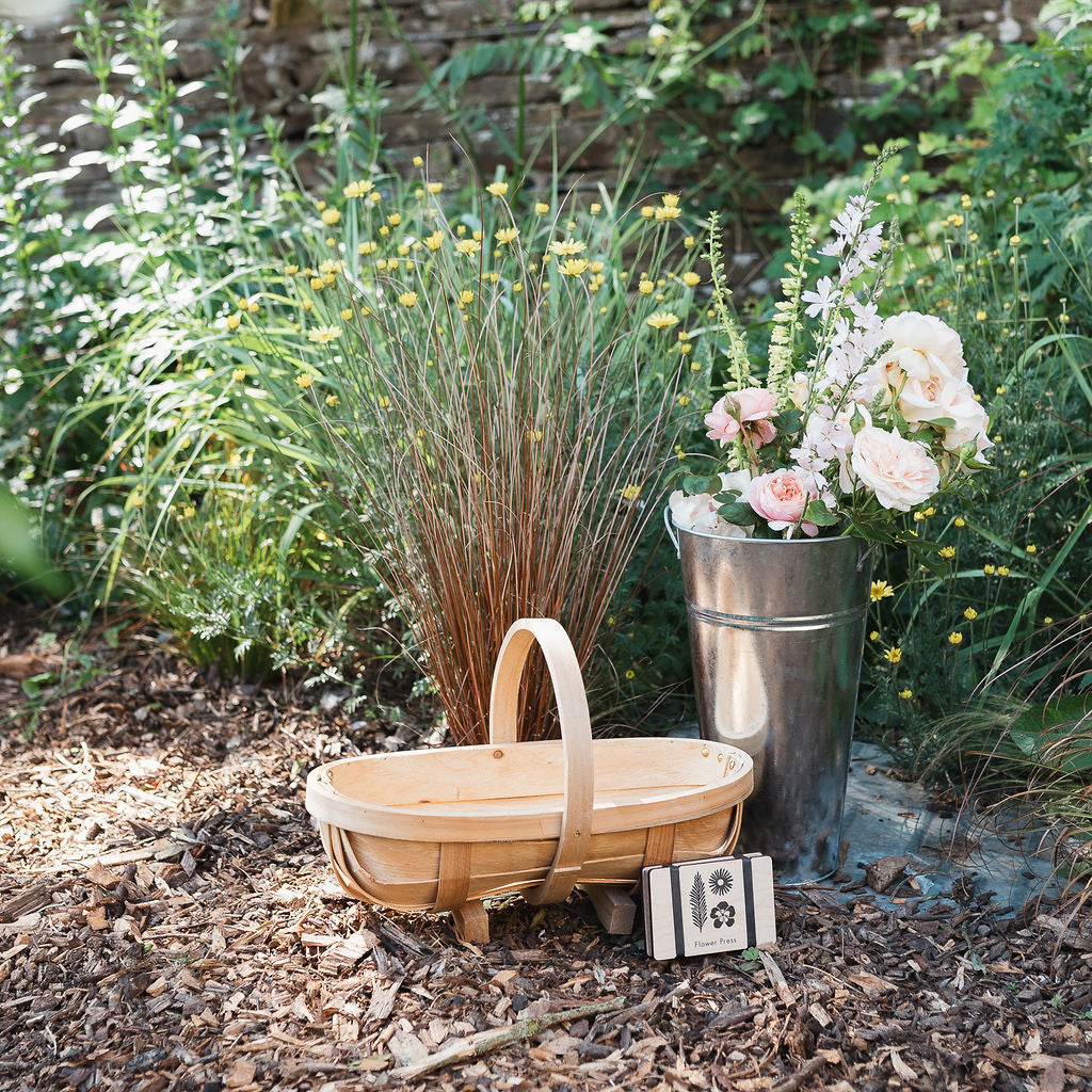 Wooden basket and metal bucket with flowers in a garden setting