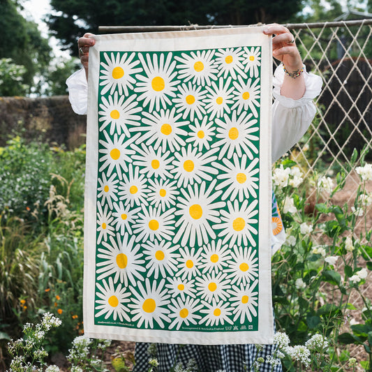 Person holding a print of daisy pattern in a garden