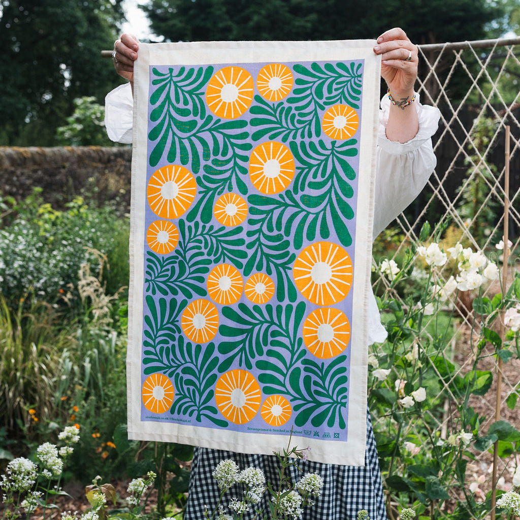 Person holding a colorful floral patterned towel in a garden setting