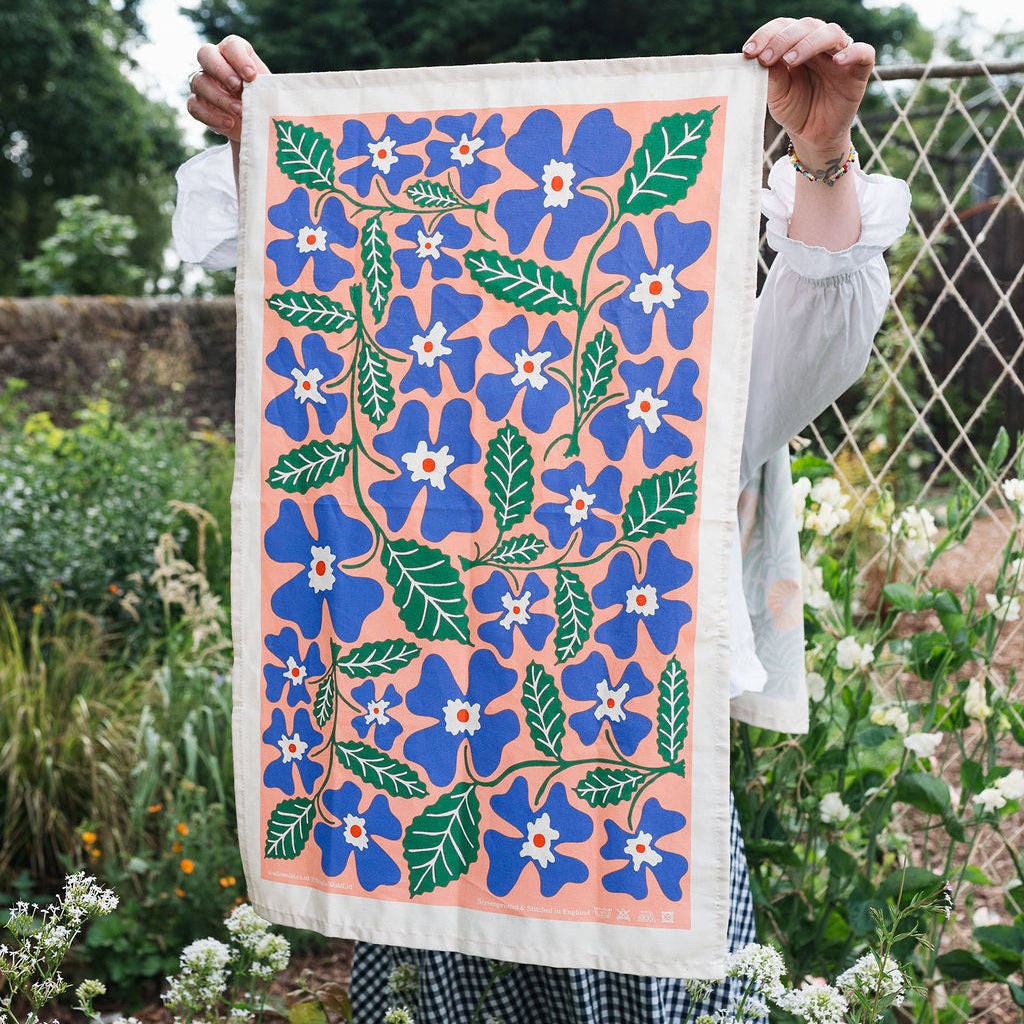 Person holding a floral patterned towel in a garden setting