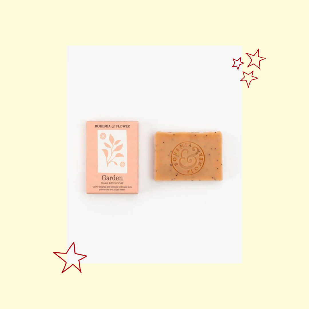 Bar of soap and its packaging on a white card with decorative stars on a light yellow background